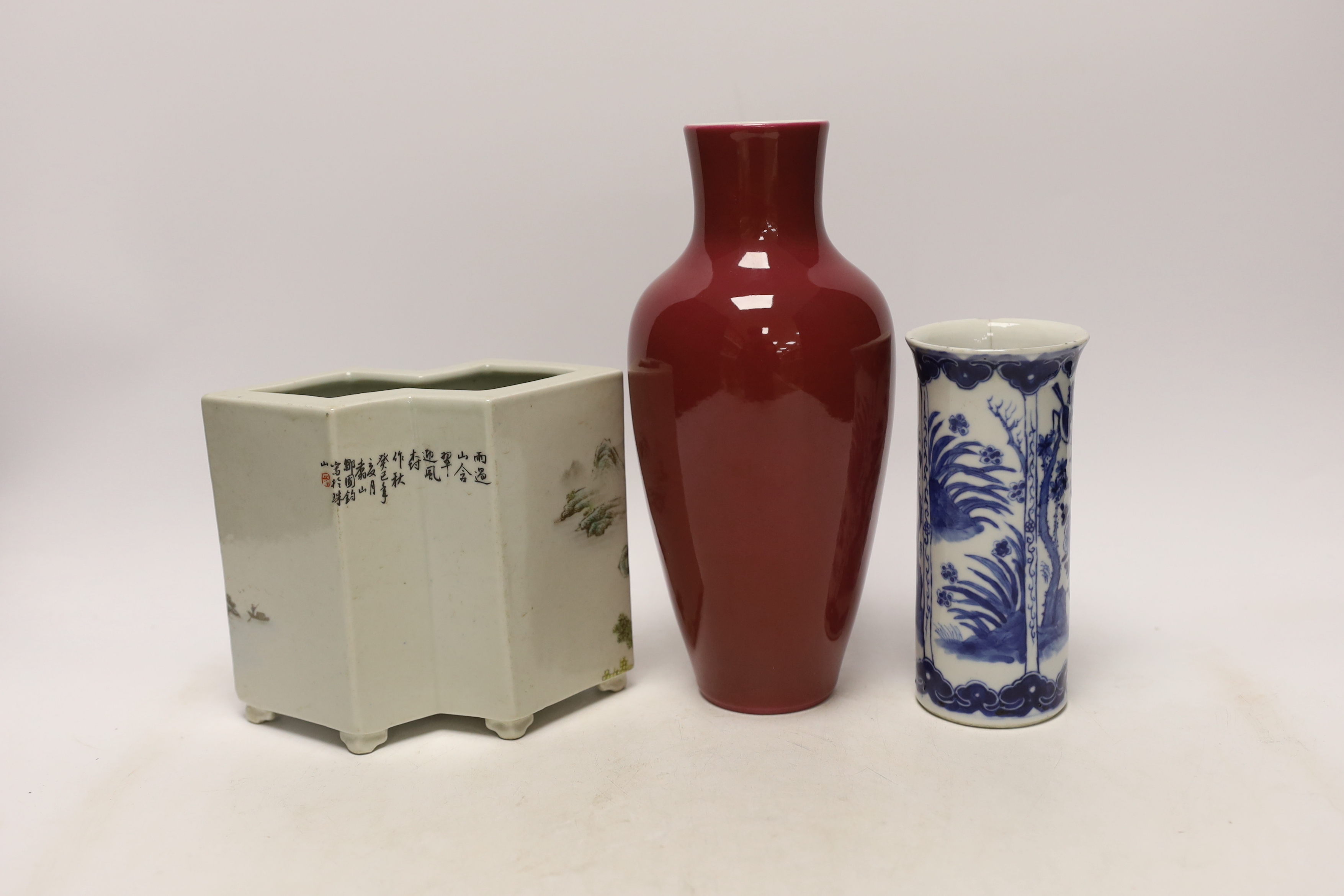 An early 20th century Chinese blue and white cylindrical vase, a ruby ground vase and an enamelled porcelain double lozenge vase, largest 24cm high (3)